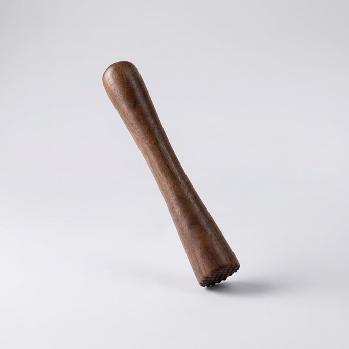 Wooden cocktail muddler in dark walnut with a flat textured crushing head, tapered handle