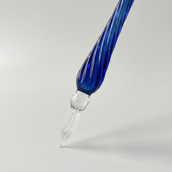 Hand-blown glass dip pen with a spiraling cobalt blue barrel, transparent clear glass nib