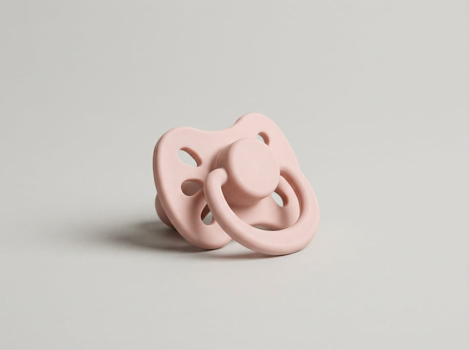 Silicone pacifier in soft blush pink with a rounded orthodontic shield