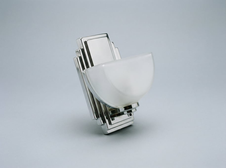 Art deco wall sconce in polished chrome with a frosted glass half-moon shade and a geometric stepped