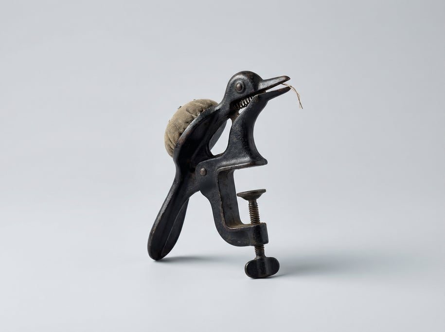 Vintage cast iron sewing bird table clamp in patinated black iron with a spring-loaded beak and pin