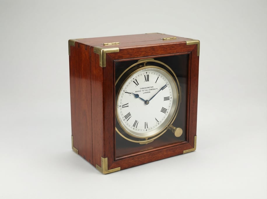 Marine chronometer in a brass-bound mahogany box with a gimbal-mounted white enamel dial face and bl