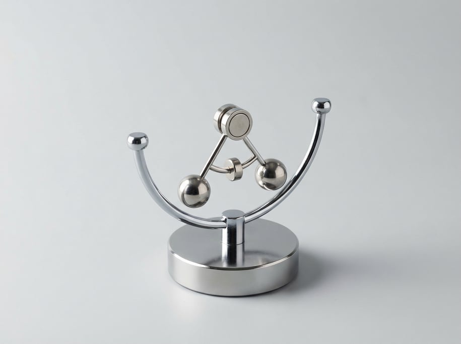 Desktop perpetual motion balance toy with a chrome pendulum arm, magnetic base disc