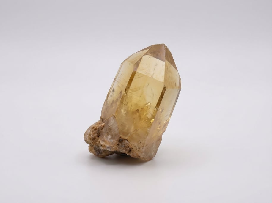 Raw citrine crystal point in warm honey yellow with a natural hexagonal prism shape and a rough matr