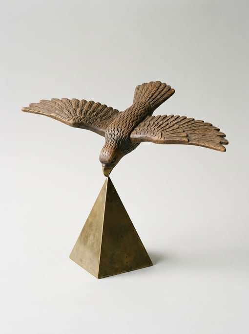 Wooden balancing eagle toy on a brass pyramid stand with outstretched wings, a weighted beak