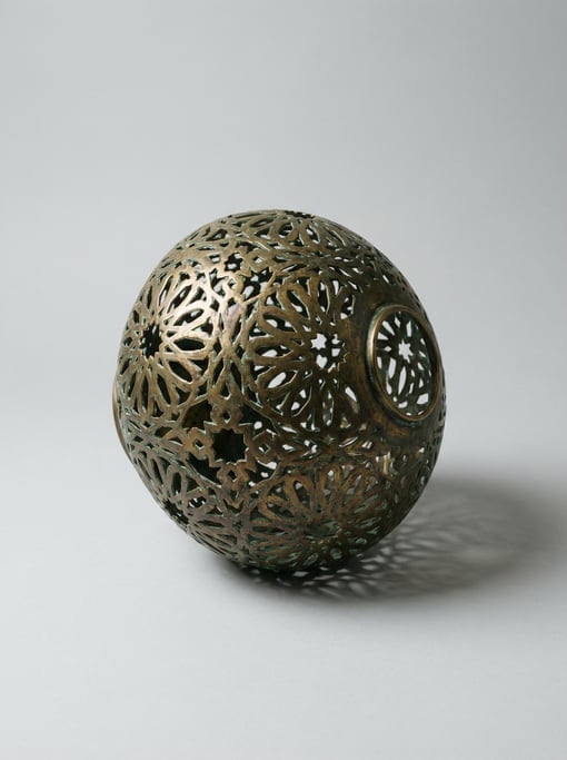 Moroccan pierced brass pendant lamp shade with intricate geometric star cutouts casting patterned li