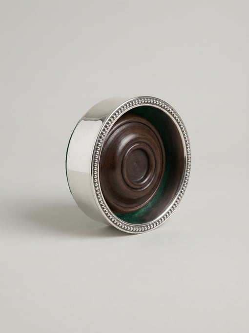 Silver-plated wine bottle coaster with a turned wooden base, beaded rim