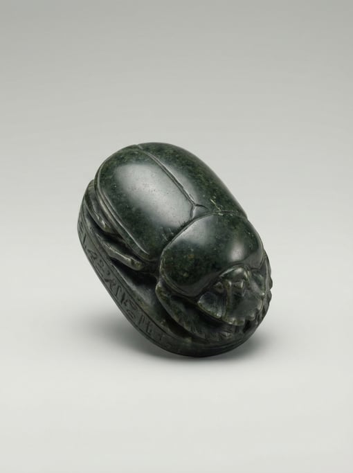 Carved soapstone scarab beetle in dark green with hieroglyphic base markings, folded wing detail