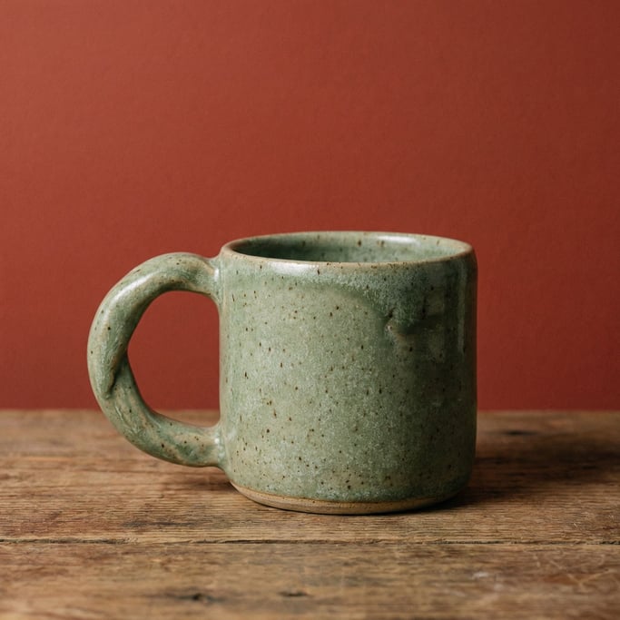 Handmade stoneware mug in speckled sage green with an organic handle