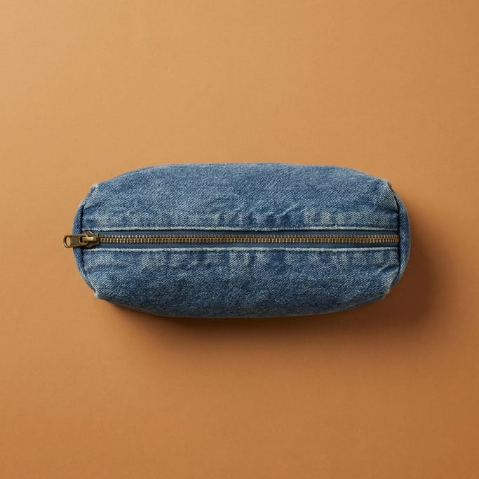 Canvas pencil case in washed denim blue with brass zipper, softly stuffed and centered