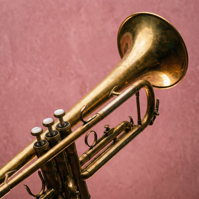 Brass trumpet with a warm golden patina and three pearl valve buttons, rim light tracing the bell