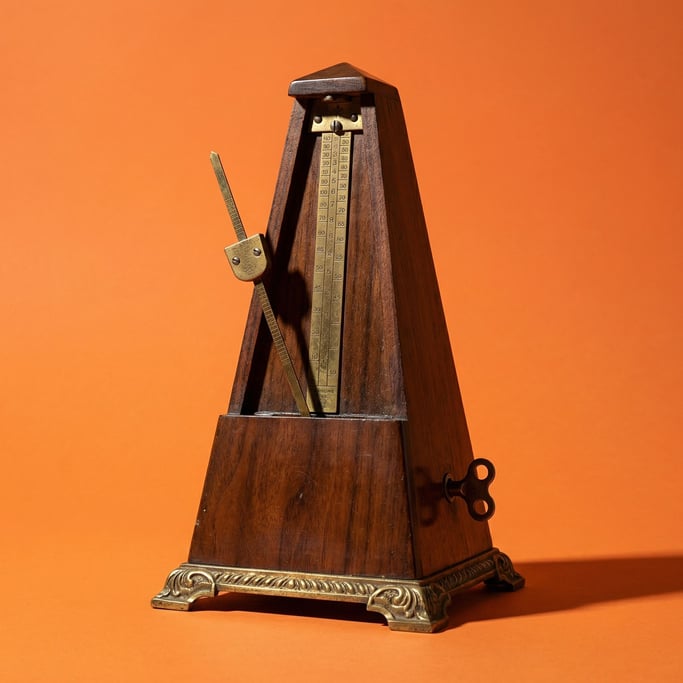 Vintage mechanical metronome in dark walnut with a brass pendulum, studio key light from the left