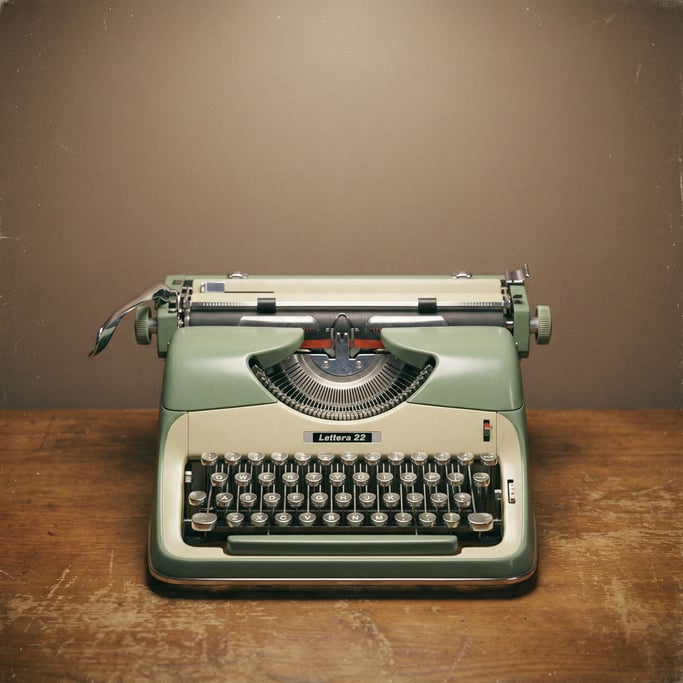 Vintage manual typewriter in two-tone green and cream with chrome accents, overhead soft light