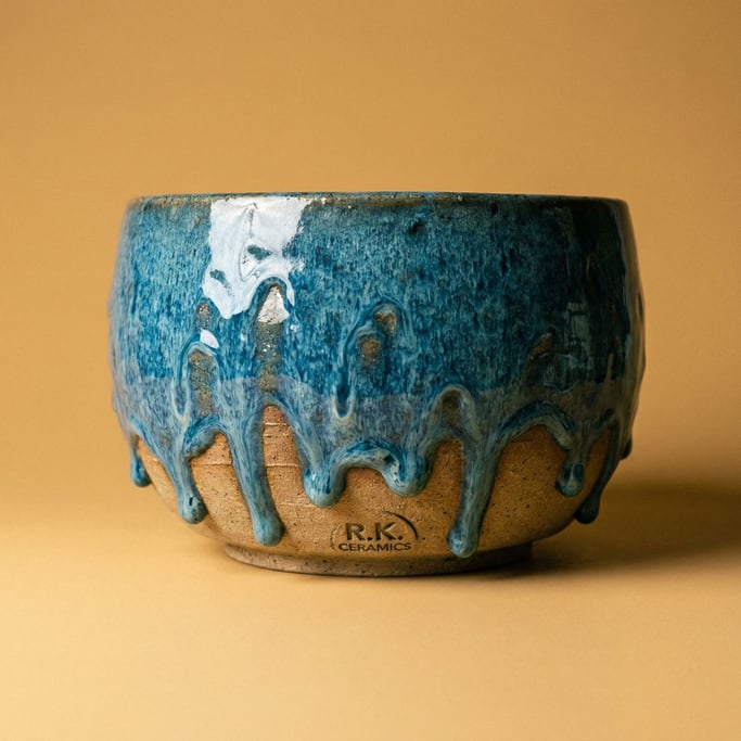 Hand-thrown ceramic bowl with drip glaze in ocean blue over raw clay