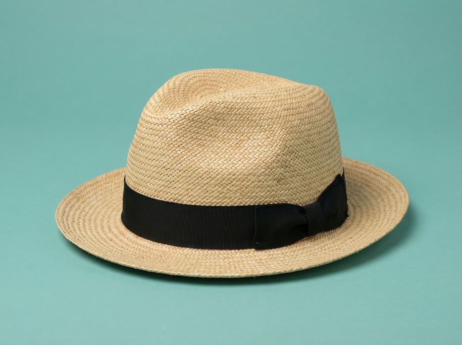 Woven straw Panama hat with a black grosgrain band, soft studio fill light