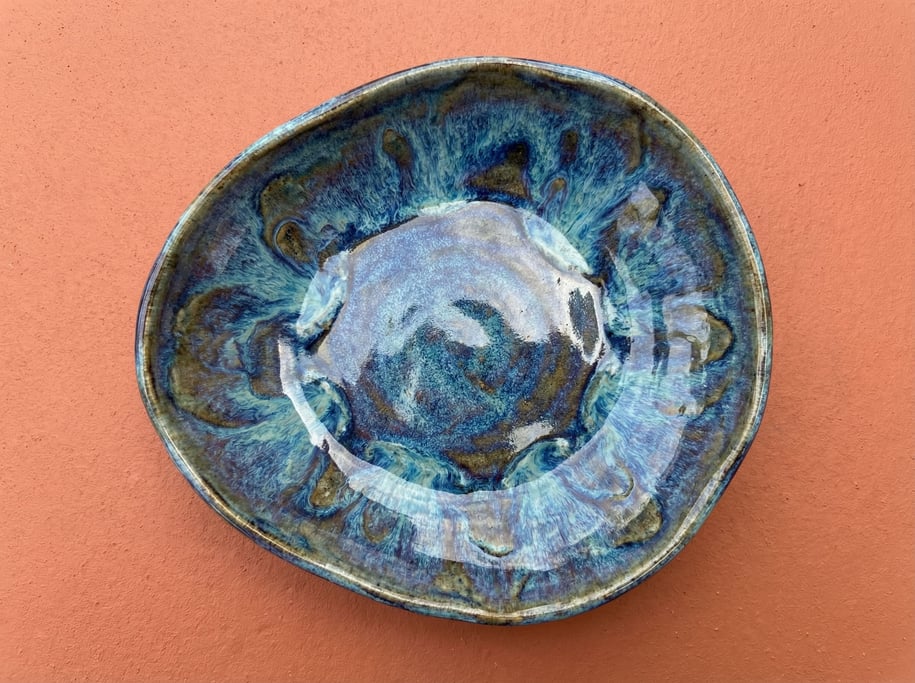 Decorative ceramic dish in an organic pebble shape with a reactive blue glaze