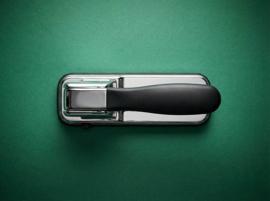 Desktop hole punch in heavy chrome with a matte black handle, overhead studio light