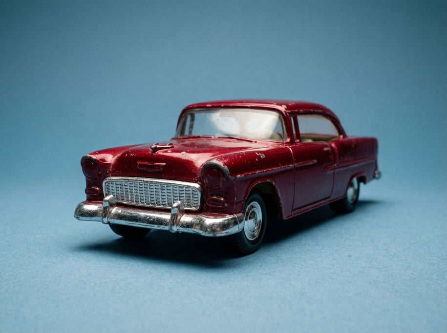 Die-cast vintage toy car in cherry red with chrome bumpers, studio two-point lighting