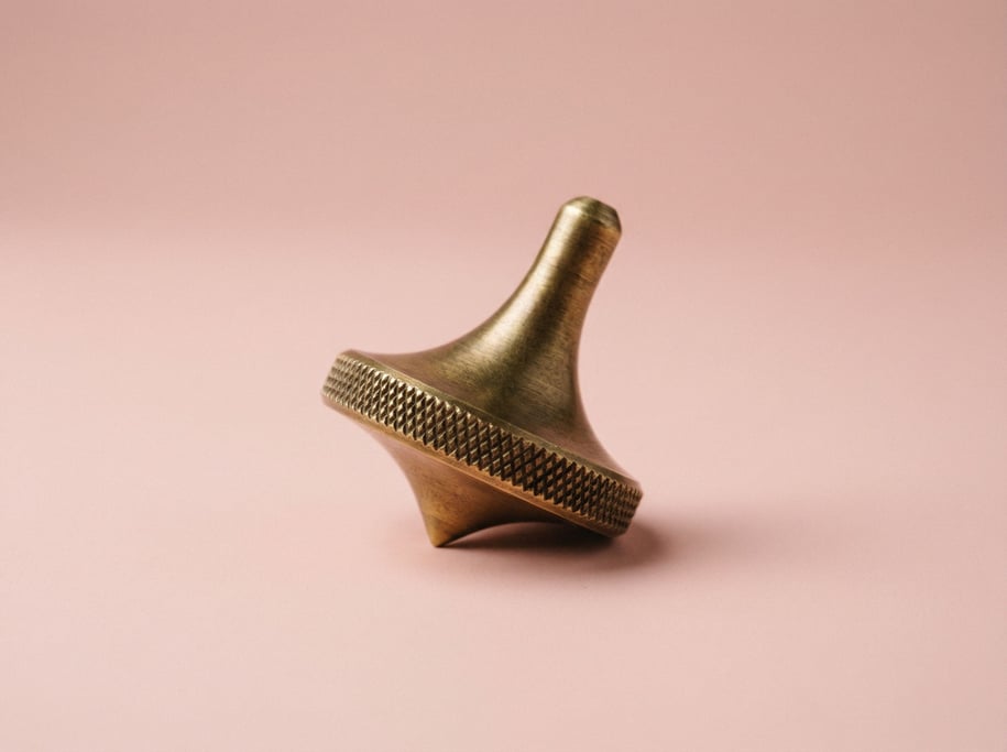 Brass spinning top with a knurled grip, captured mid-rest on its point