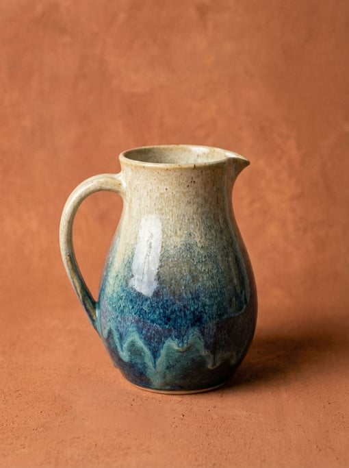 Stoneware pitcher in reactive glaze shifting from cream to blue