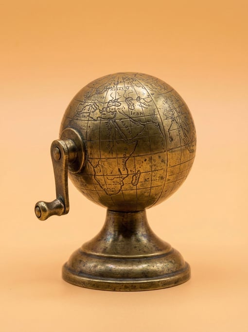 Globe-shaped pencil sharpener in antique brass with a tiny crank handle, macro studio lighting