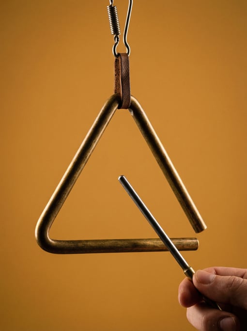 Brass triangle instrument with a metal striker, suspended from a clip