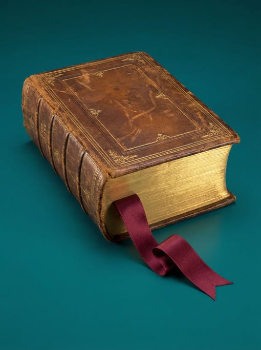 Thick leather-bound hardcover book with gilt page edges and a ribbon bookmark