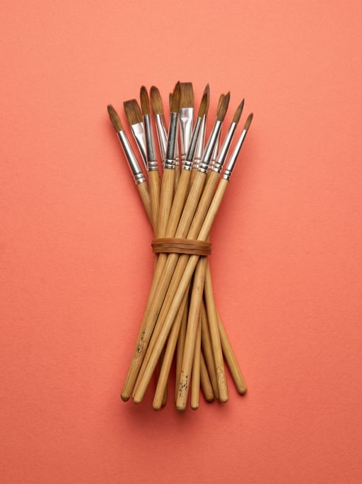 Fan-shaped set of watercolor brushes with bamboo handles, bound by a rubber band