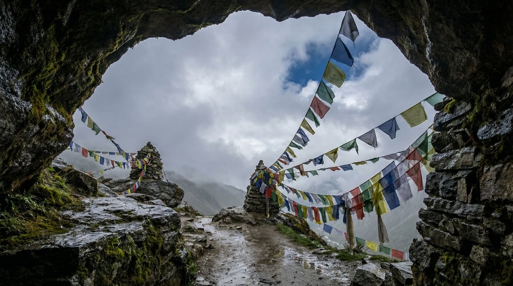 A mountain pass with colorful prayer flags strung between cairns