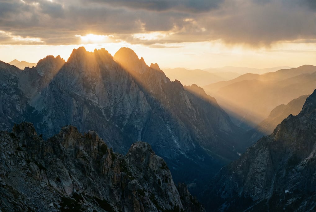 A jagged granite ridge at dawn, the first rays of sunlight hitting only the highest peaks while vall