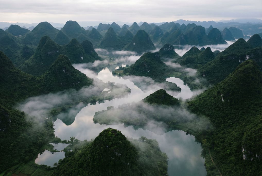 Karst landscape with conical green hills, morning mist pooling in the valleys between them