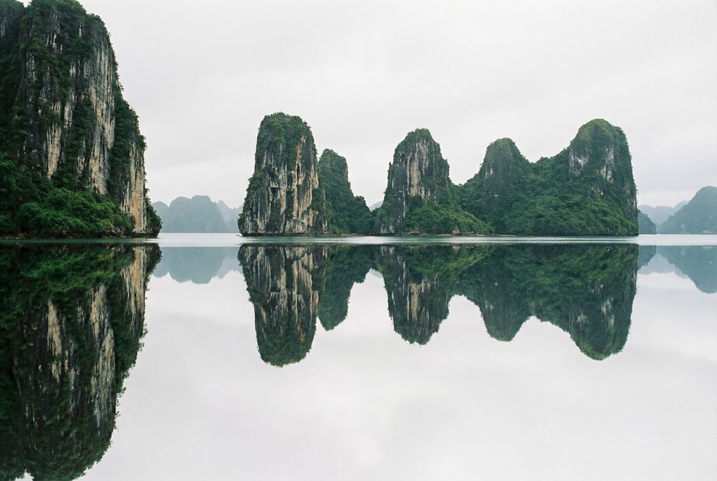 Limestone karst towers rising from calm emerald sea, vertical green cliffs reflected in still water (uhonyn0a)