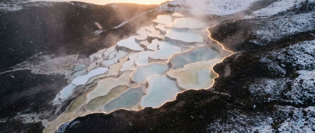 Hot spring terraces, calcium carbonate pools cascading down a hillside in white and pale blue (i0r6wyqm)