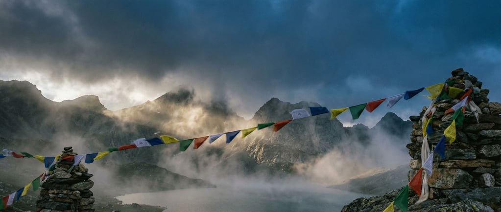 A mountain pass with colorful prayer flags strung between cairns (mtg3iwib)