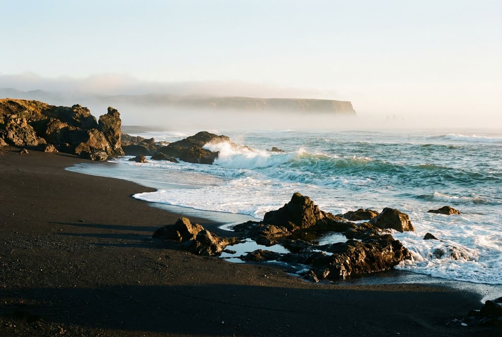 Volcanic black sand beach with turquoise waves breaking on shore, stark contrast of dark and bright (6rfxgcoq)