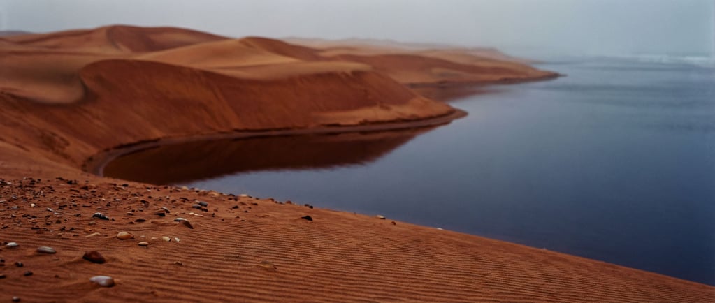 Red sand dunes meeting the Atlantic Ocean (ym2pfld6)