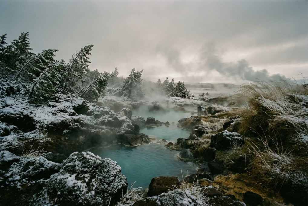 Snow-covered volcanic hot springs, steam rising from turquoise mineral pools into sub-zero air (jujhyyi6)