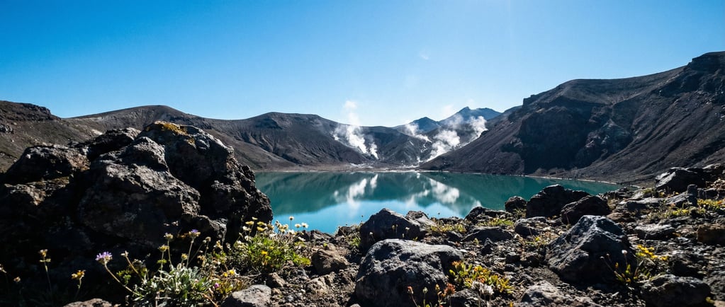 A volcanic caldera lake, perfectly still turquoise water surrounded by dark ash-covered slopes and w (vz9klbgc)