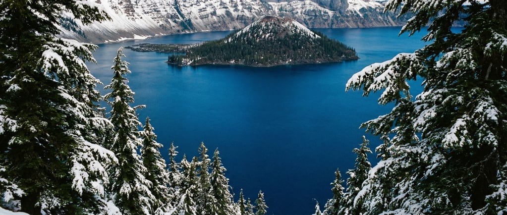 A crater lake in Oregon viewed through a frame of snow-laden conifers