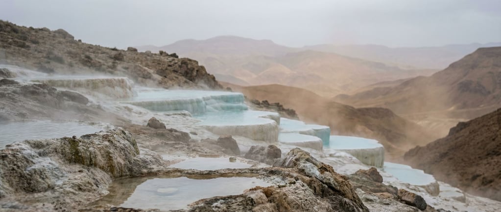 Hot spring terraces, calcium carbonate pools cascading down a hillside in white and pale blue (rivx3mm)