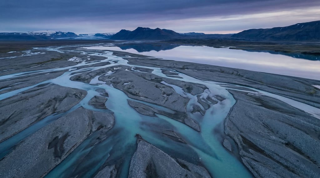 Turquoise glacial meltwater river braiding across a gray gravel plain, seen from above (9aoma09n)