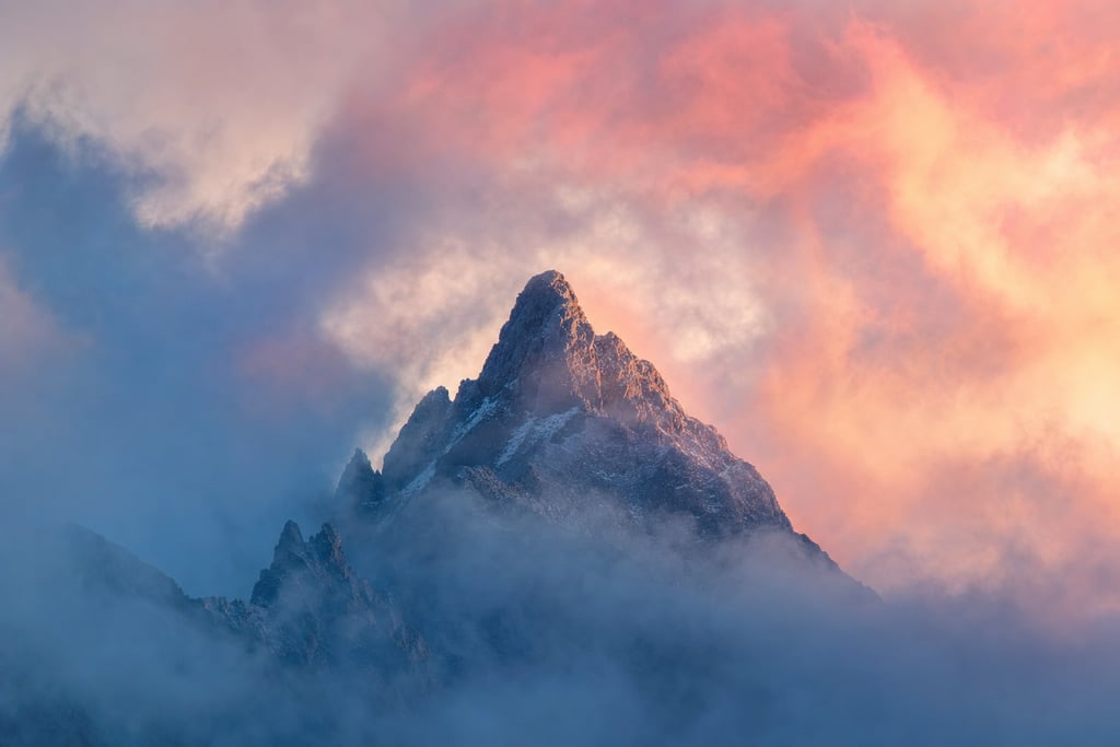 Foggy mountain peak with surreal, colorful clouds swirling in the sky