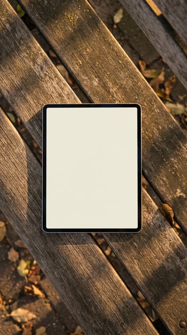 Tablet lying flat on a park bench, blank solid ivory screen with no content