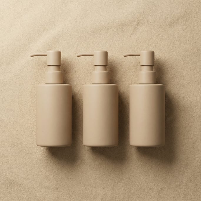 Lotion pump bottle in matte sand, three in a row, completely blank with no text labels or branding