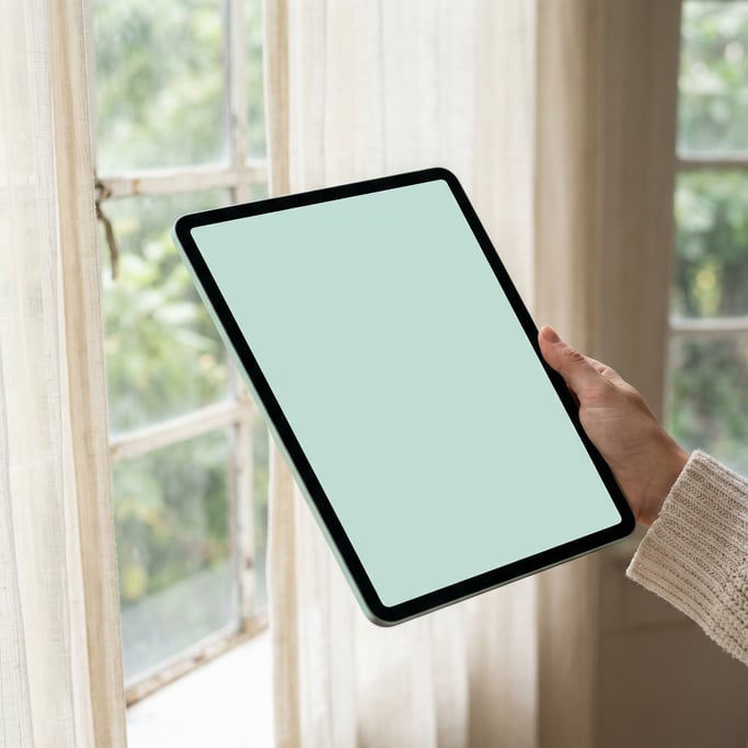 Hand holding a large tablet near a window with soft natural light