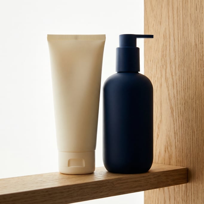 Squeeze tube in matte cream and pump dispenser bottle in matte navy