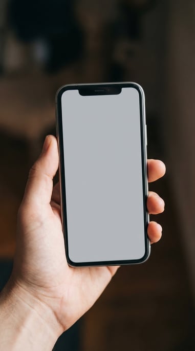 Hand holding a modern smartphone against a dark blurred background