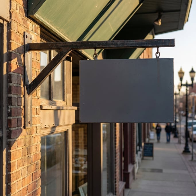 Double-sided projecting sign hanging from a metal bracket on a storefront