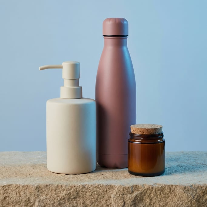 Soap dispenser in matte cream and sports bottle in matte dusty rose and deodorant stick container in