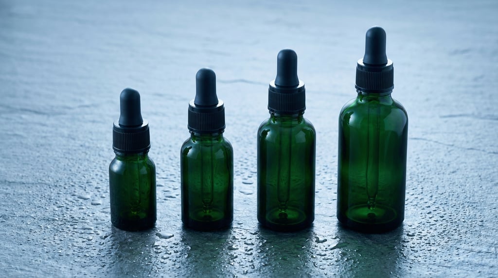 Dropper bottle in dark green glass, row of four in graduated heights